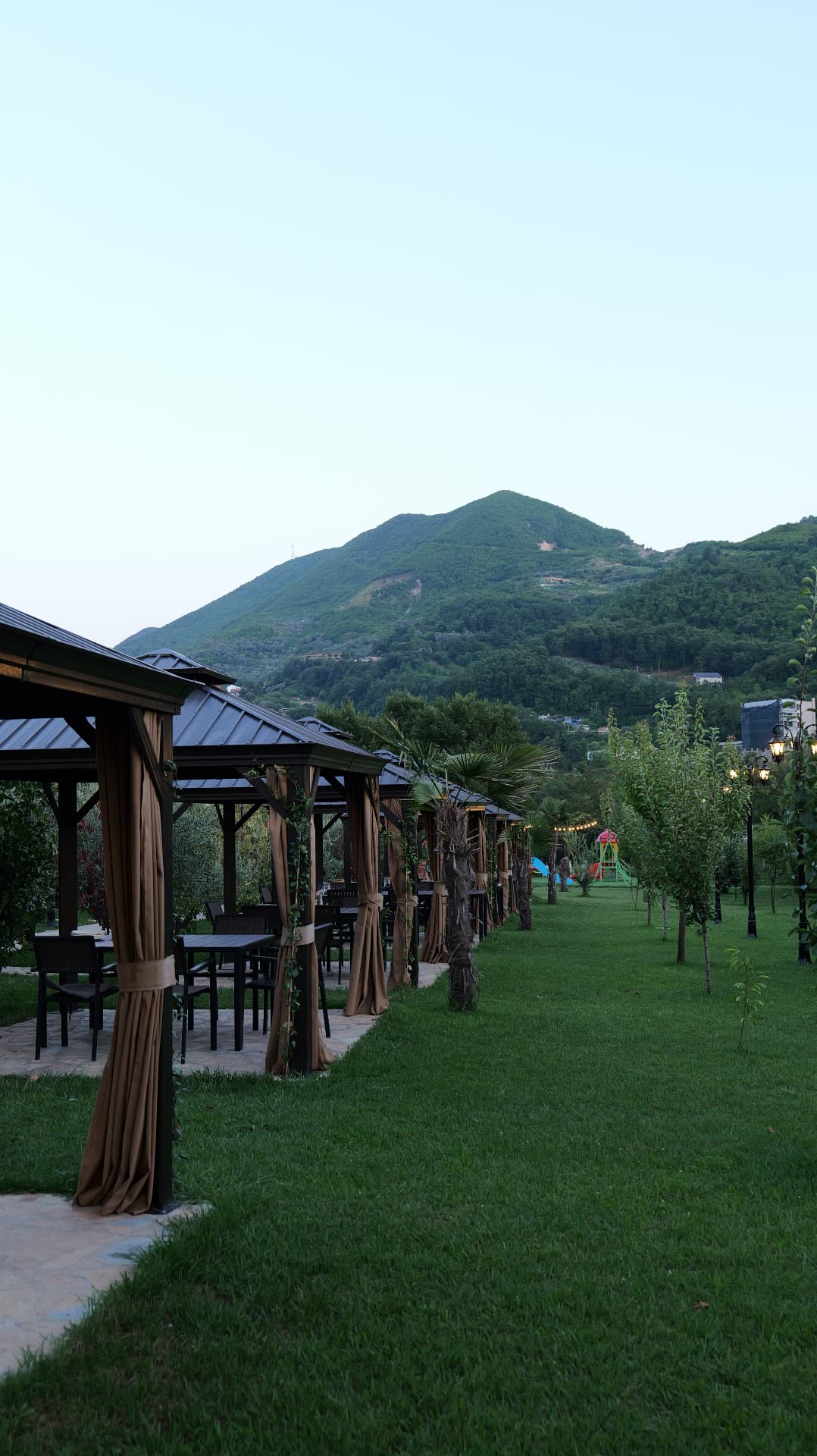 Row of gazebos on the lawn with the green mountain behind OKO Farm
