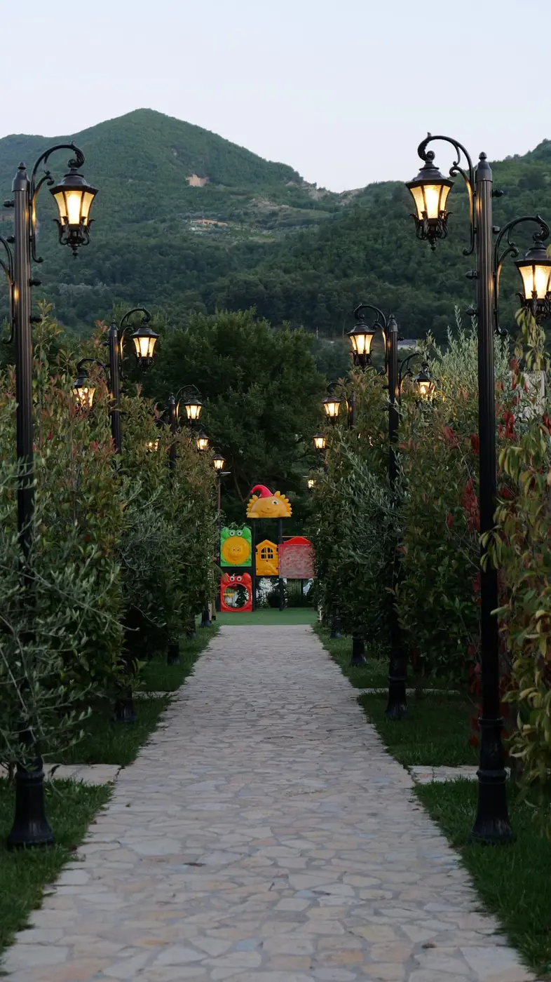 Stone path lined with lamp posts leading to the playground at dusk